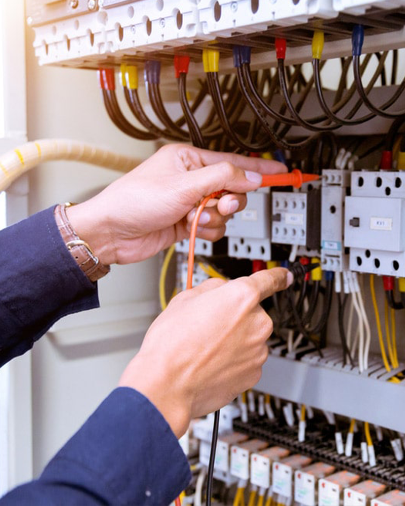 Anchor Electric electrician in Sarasota testing commercial electrical panel components with multimeter