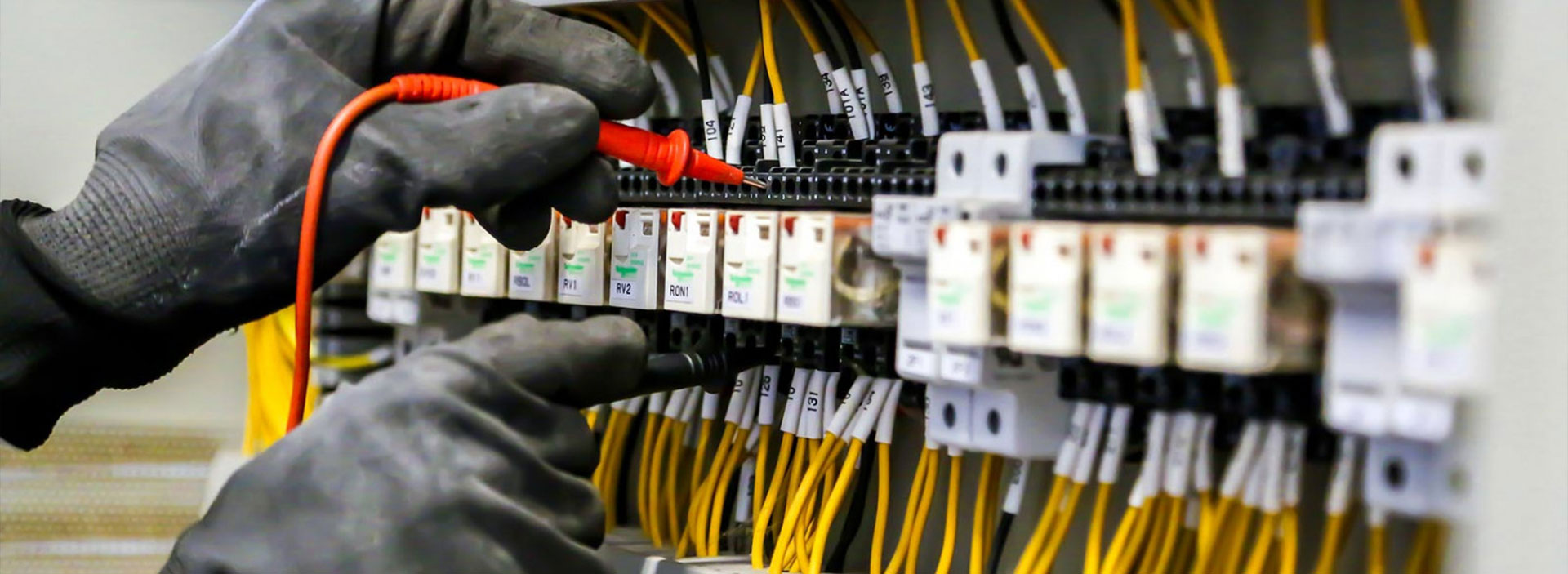 Sarasota electrician from Anchor Electric testing industrial control panel circuits with a multimeter tool.