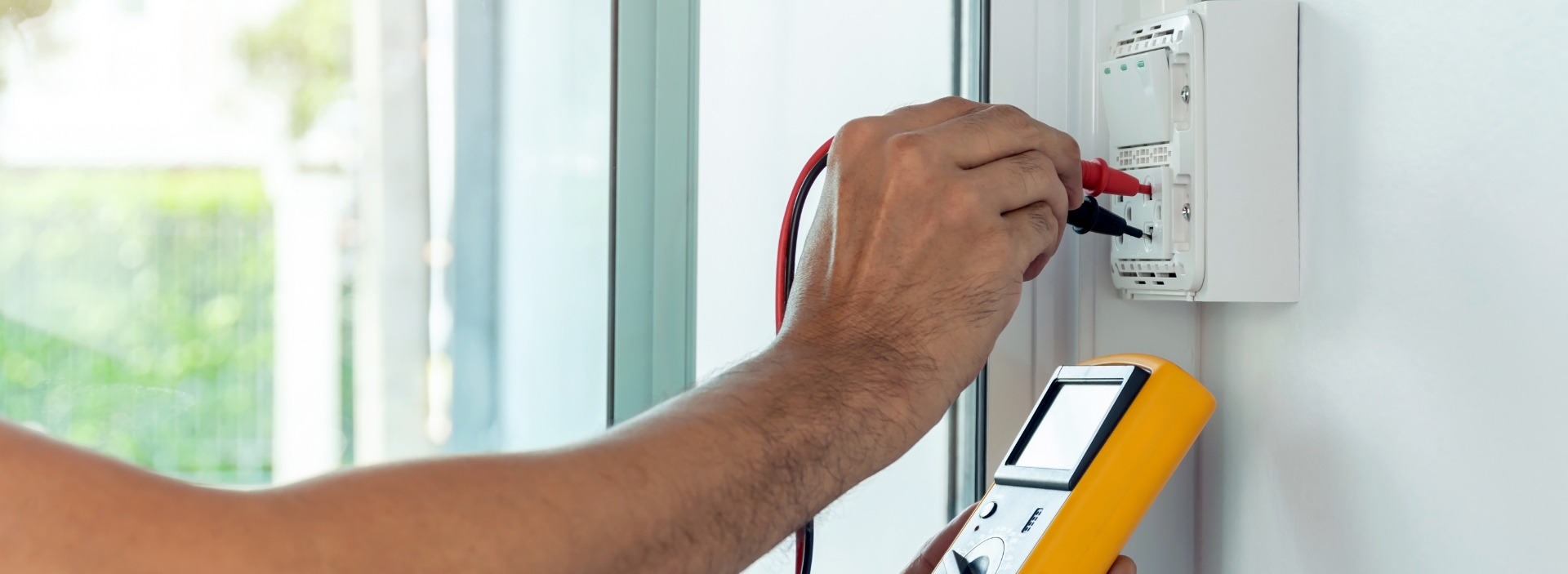 Electrician from Anchor Electric testing wiring with a digital multimeter at a Sarasota home