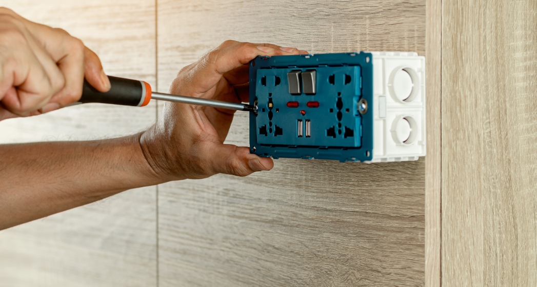 Sarasota electrician from Anchor Electric installing a modern wall outlet with USB ports on wood paneling