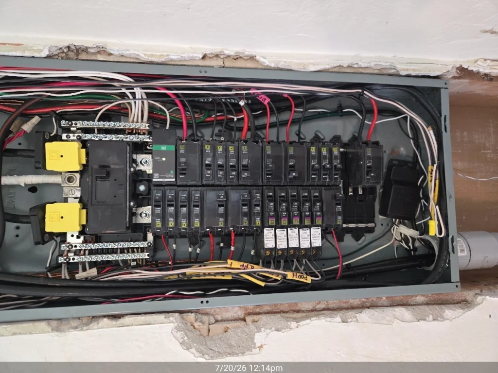 Open residential electrical panel with circuit breakers and wiring